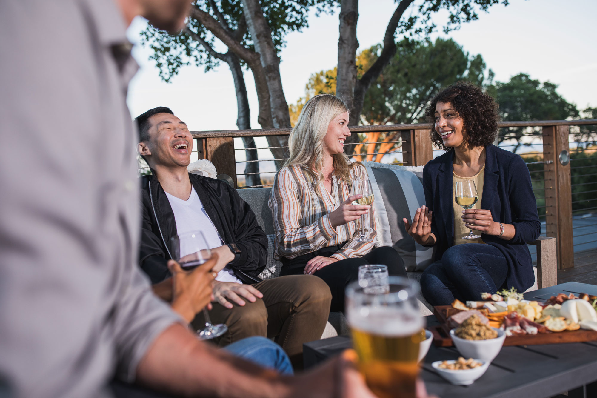Friends laugh together while enjoying drinks and food outside