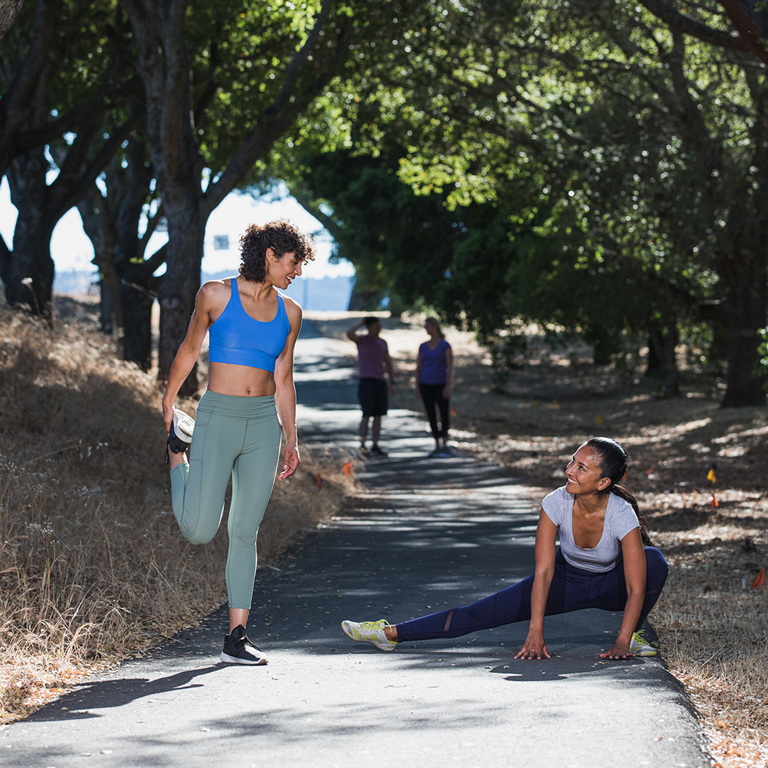 Two female joggers take a stretch break on a trail